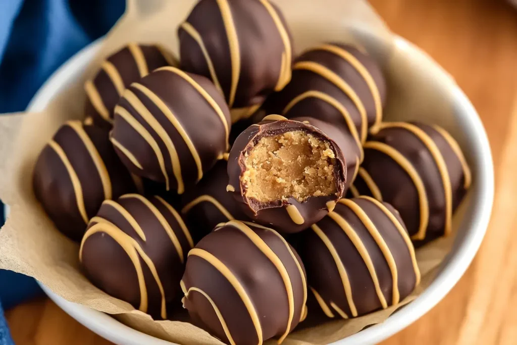 Chocolate peanut butter balls with a decorative drizzle of peanut butter, arranged in a white bowl lined with parchment paper.