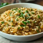 A bowl of French Onion Soup Rice garnished with fresh parsley, highlighting its golden-brown color and fluffy texture.