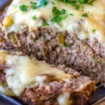 Philly cheesesteak meatloaf slice revealing layers of ground beef, melted cheese, and bell peppers, garnished with fresh parsley for added flavor.