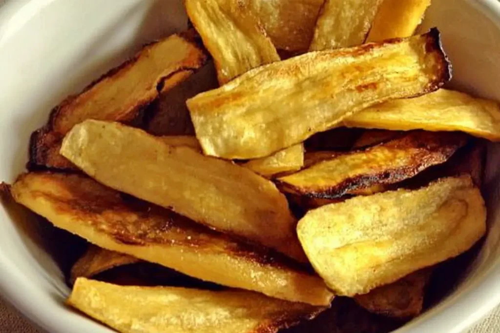 Thick-sliced plantain chips cooked to a golden brown, displayed in a bowl, emphasizing alternative slicing styles.